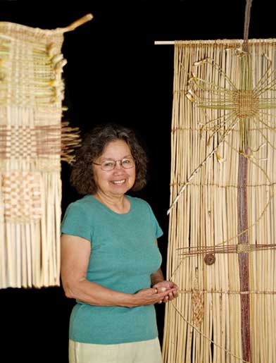 Pat COurtney GOld standing with her wall hangings at the School for Advanced Research